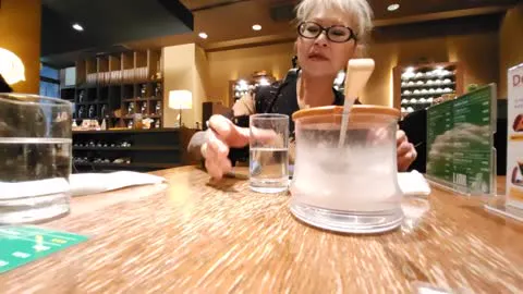 A participant seated across a restaurant table with glasses and a water pitcher.